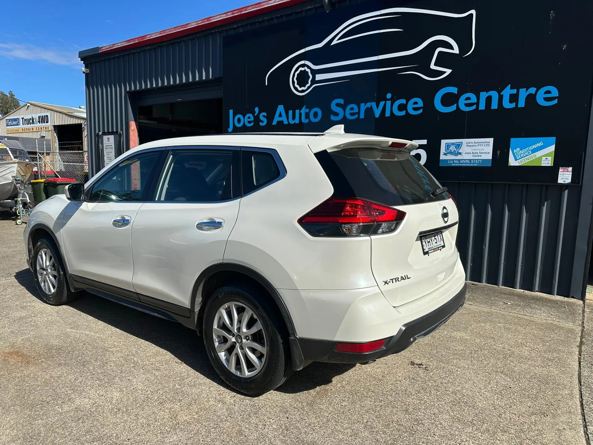 Car parked in front of Joe's Auto Service Centre's workshop and signage