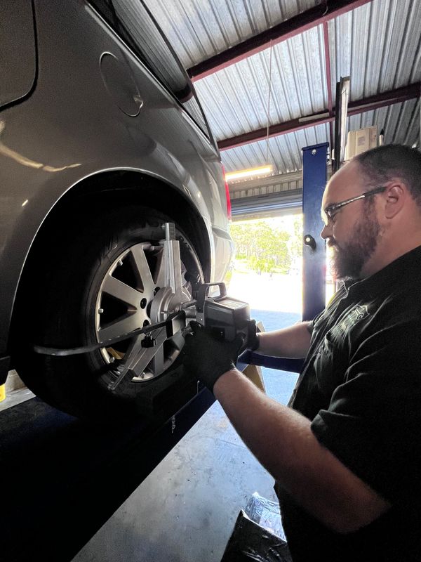Joe's Auto Service Centre mechanic adjusting wheel alignment angles in the Forster workshop